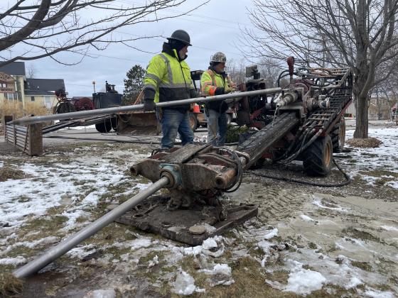 Mike Young and Joe Hess use a trenching machine, which creates a narrow and deep channel for fiber optic cables to be installed under the Lake Leelanau Narrows in March. Enterprise photo by Brian Freiberger