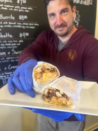 New Bohemian Cafe owner Kevin Murphy is pictured with one of his restaurant week specials, the spicy bacon breakfast burrito. This is the first year his cafe is participating in Northport-Omena Restaurant Week.